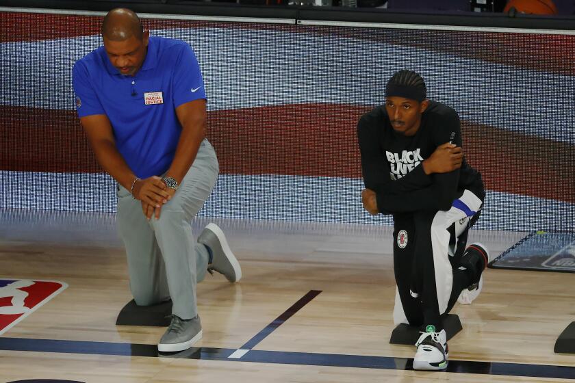 Los Angeles Clippers' Lou Williams, right, and head coach Doc Rivers look on during the national anthem.