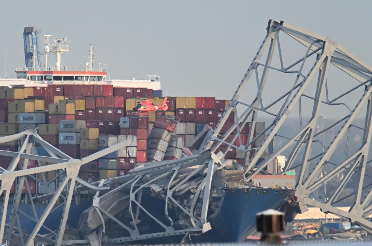 The steel frame of the Francis Scott Key Bridge sits on top of a container ship in Baltimore.