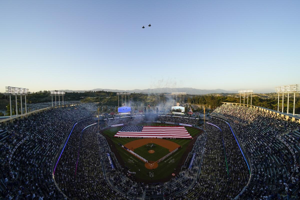 Planes fly over Dodger Stadium as the national anthem is sung before a baseball game between the Cincinnati Reds and the Los Angeles Dodgers in Los Angeles, Thursday, April 14, 2022. (AP Photo/Ashley Landis)