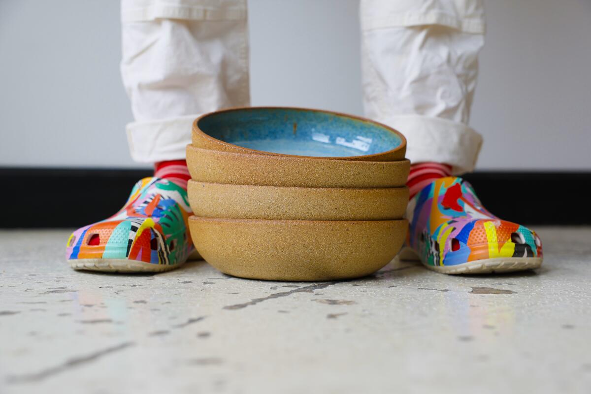 Ceramic pasta bowls rest near colorful Crocs.