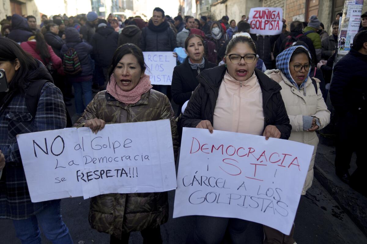A crowd of protesters hold signs denouncing the failed coup attempt during a demonstration in La Paz, Bolivia