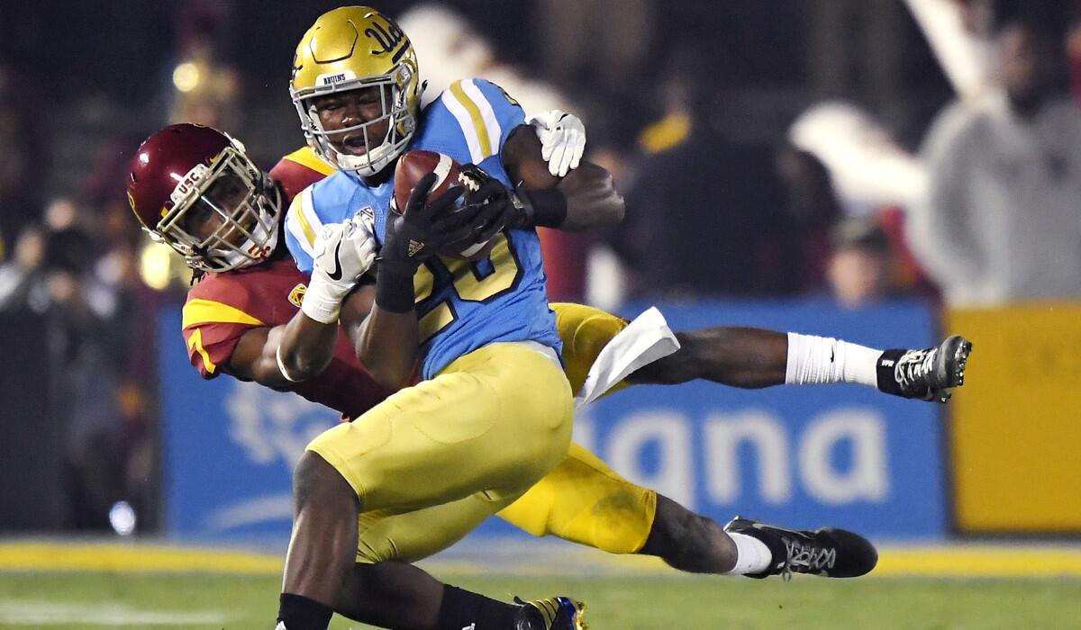 UCLA running back Brandon Stephens, front, is tackled by USC defensive back Marvell Tell III after making a catch during the first half Saturday.