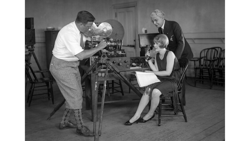 May 28, 1928: USC President Rufus B. von KleinSmid stands behind actress Anita Page as she takes her first lesson at the university's school of speech as Hollywood moves from silent films to talkies.