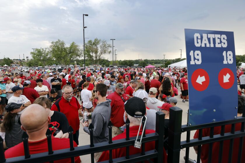 Fans wait outside the stadium during a weather delay before the first game of the NCAA Women's College World Series softball championship series between Florida State and Oklahoma on Wednesday, June 7, 2023, in Oklahoma City. (AP Photo/Nate Billings)
