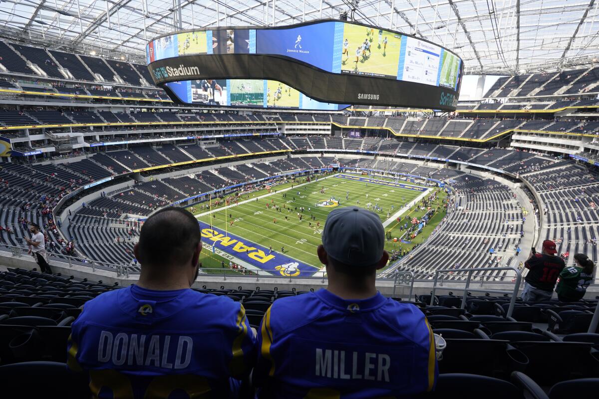 Rams fans sit in their seats at SoFi Stadium and look toward the field.