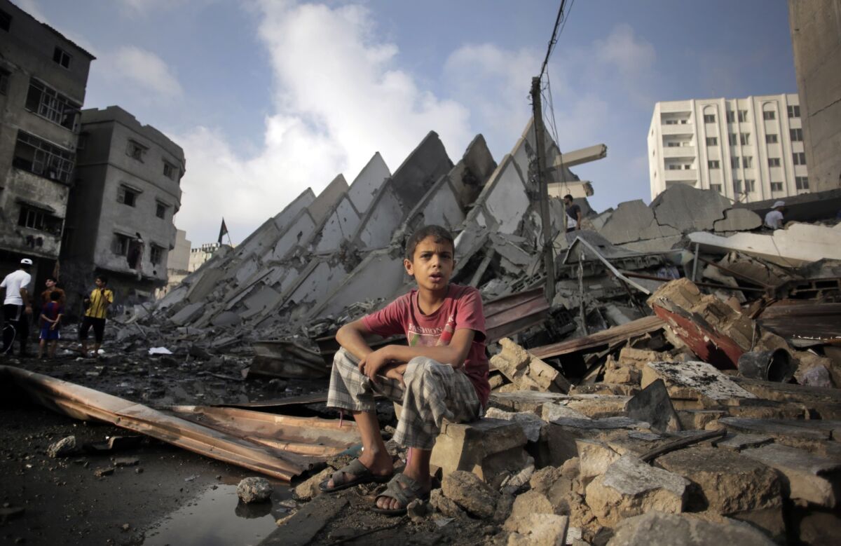 A Palestinian boy sits next to the rubble of what was a 15-story high-rise following Israeli airstrikes in Gaza City on Aug. 26.