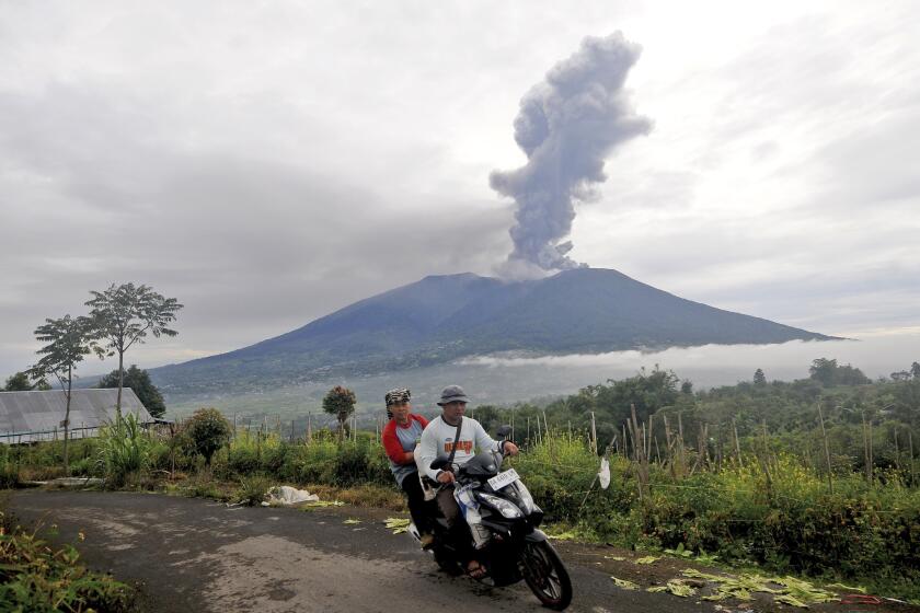 Motorists ride past by as Mount Marapi spews volcanic materials during its eruption in Agam, West Sumatra, Indonesia, Monday, Dec. 4, 2023. The volcano spewed thick columns of ash as high as 3,000 meters (9,800 feet) into the sky in a sudden eruption Sunday and hot ash clouds spread several miles (kilometers). (AP Photo/Ardhy Fernando)