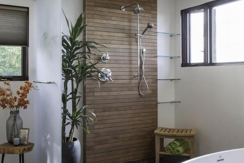 A bathroom remodeled using biophilic principles has an open space wet room with plants, a wood-look wall and a pebble floor.