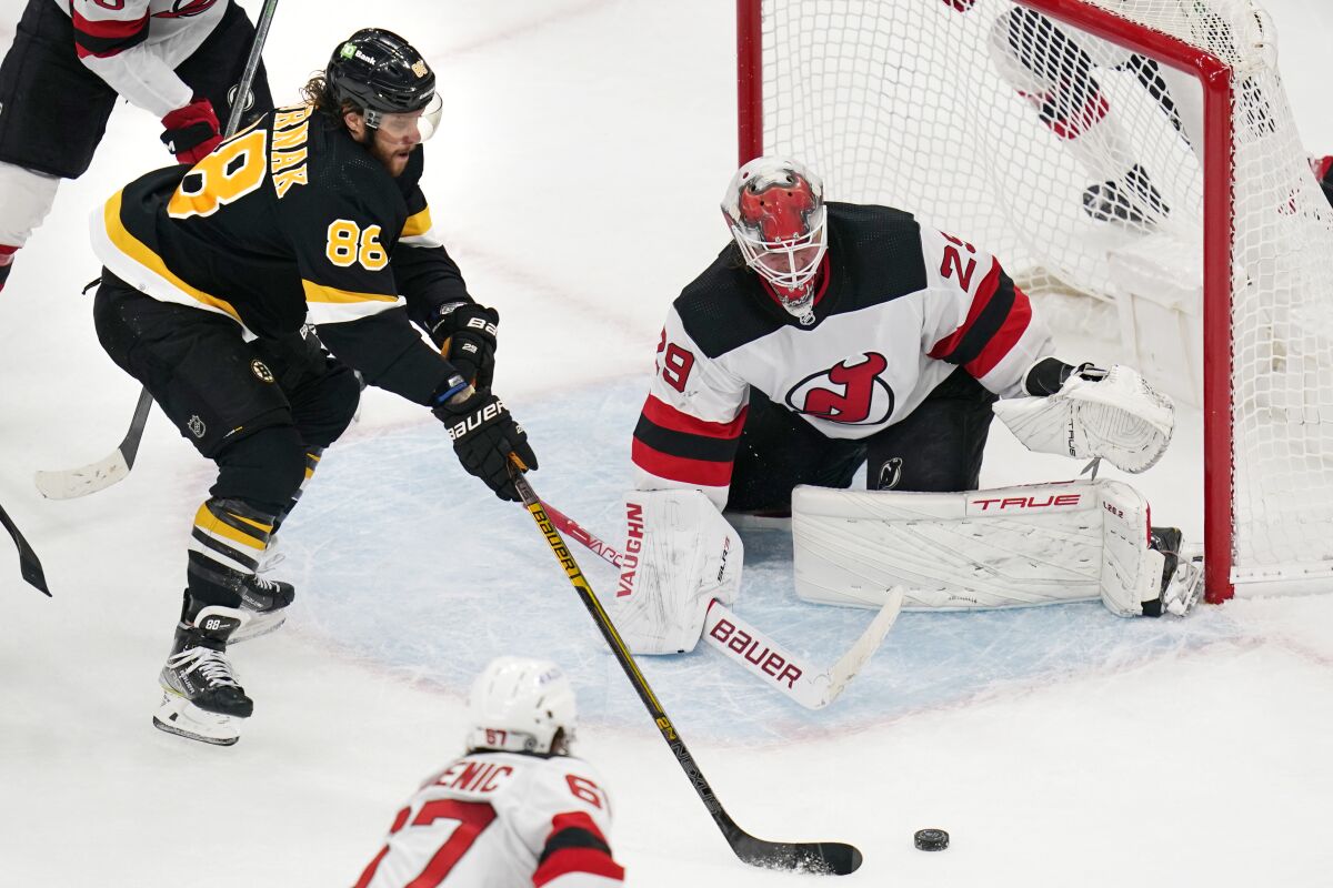Boston Bruins right wing David Pastrnak (88) tracks the puck while lining up a shot against New Jersey Devils goaltender Mackenzie Blackwood (29), on which he scored, during the third period of an NHL hockey game Tuesday, Jan. 4, 2022, in Boston. The Bruins won 5-3. (AP Photo/Charles Krupa)