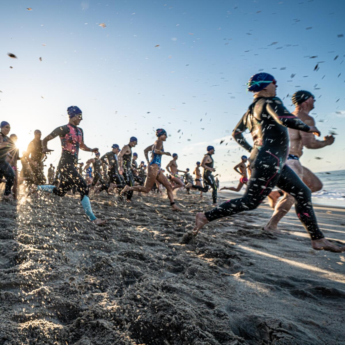 Swimmers in a triathlon running toward the ocean