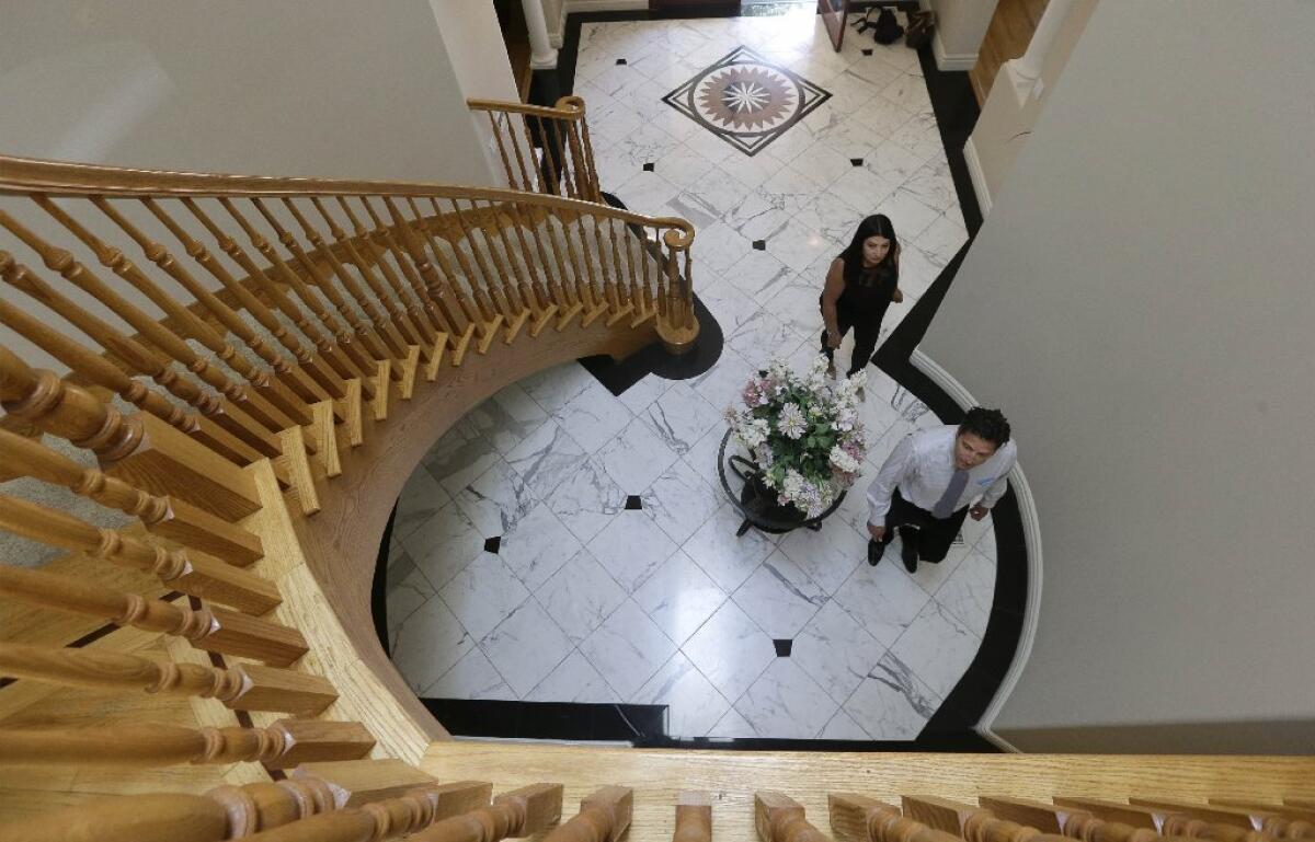 The cost of a home loan fell this week on global economic fears. Thirty-year mortgage rates in the 4% range are a boon for potential buyers like Sasha Martinez, above, looking over a home in Pacifica, Calif., with real estate agent Stephan Marshall.