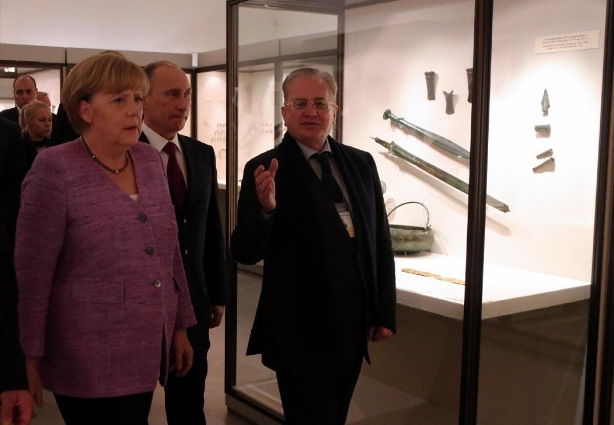 German Chancellor Angela Merkel, Russian President Vladimir Putin, center, and Hermitage Museum director Mikhail Piotrovsky visit the exhibition "Bronze Age of Europe -- Europe Without Borders" at the State Hermitage museum in St. Petersburg.