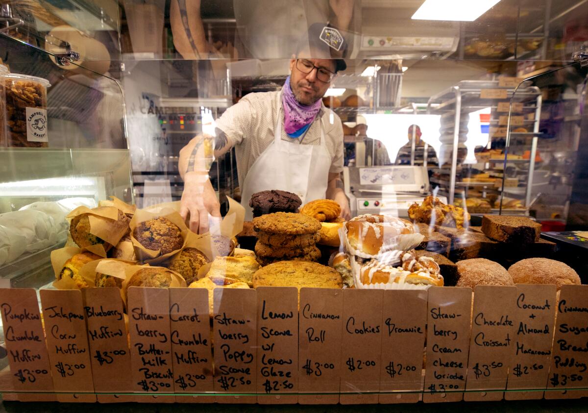 A man stands behind a case full of baked goods.