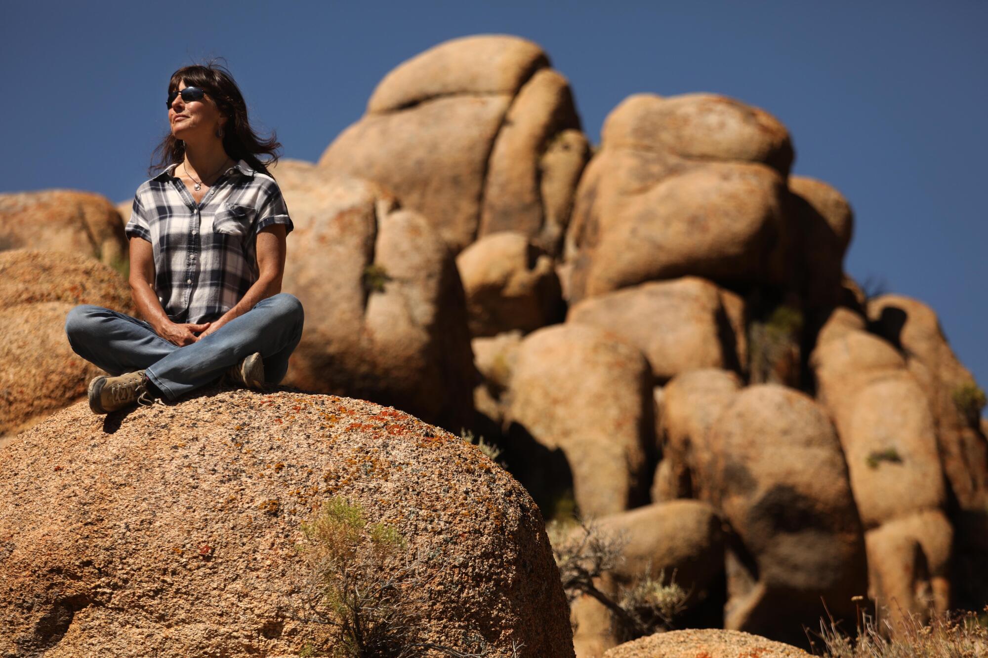 Wendy Schneider, executive director of Friends of the Inyo, sits on a rock formation in Alabama Hills National Scenic Area
