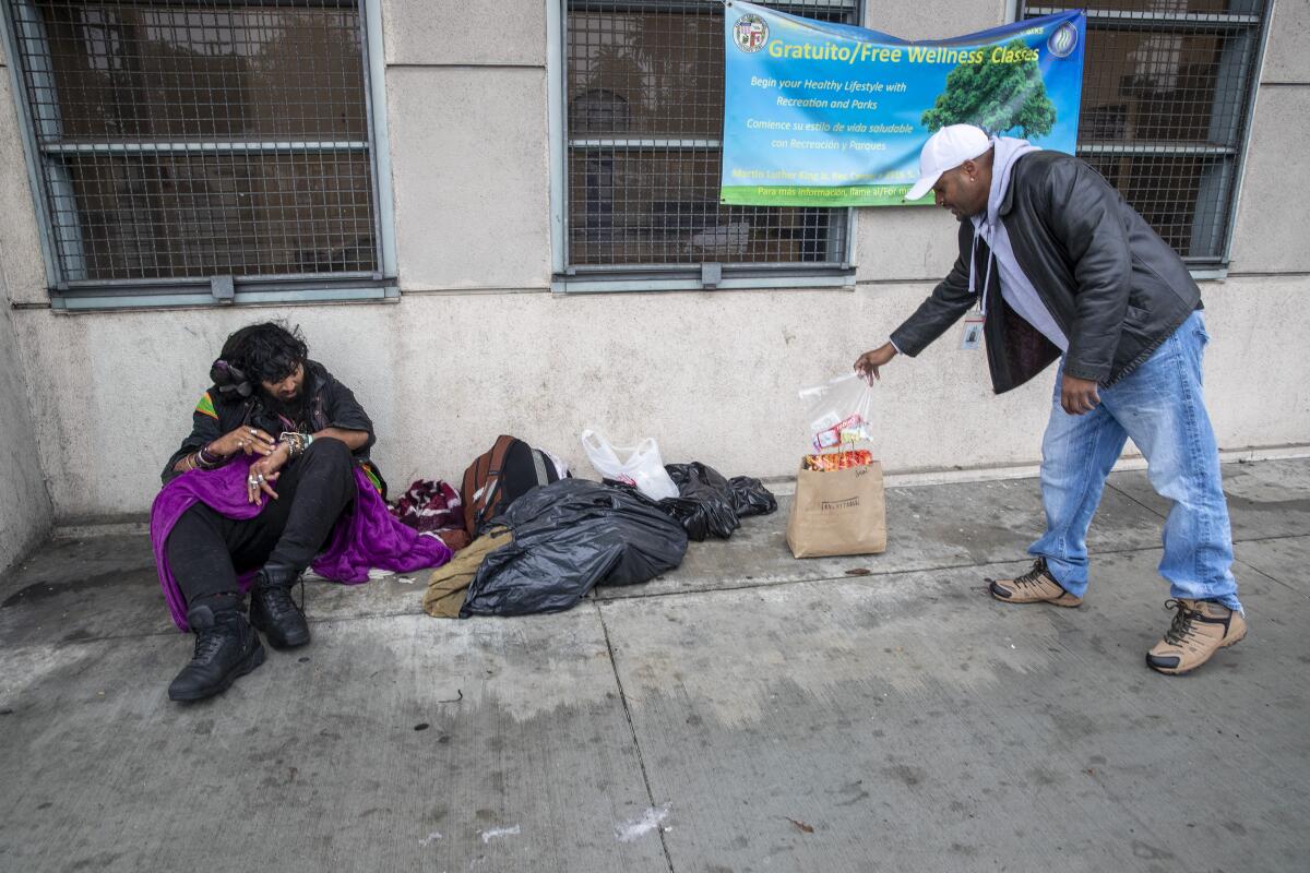 Outreach nurse Kenya Smith, right, leaves food for homeless client Davis Soto.