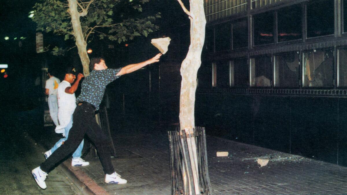 April 29, 1992: A rioter hurls a large chunk of concrete through a window of the Los Angeles Times building on 2nd Street during the Los Angeles Riots.