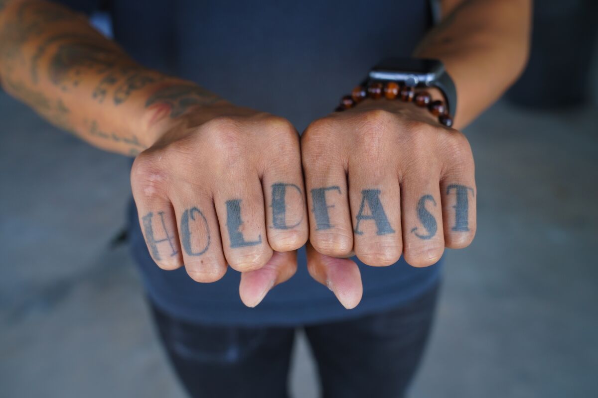 Chef Phillip Esteban during a photo shoot shows the tattoos on his hands, which say "hold fast"