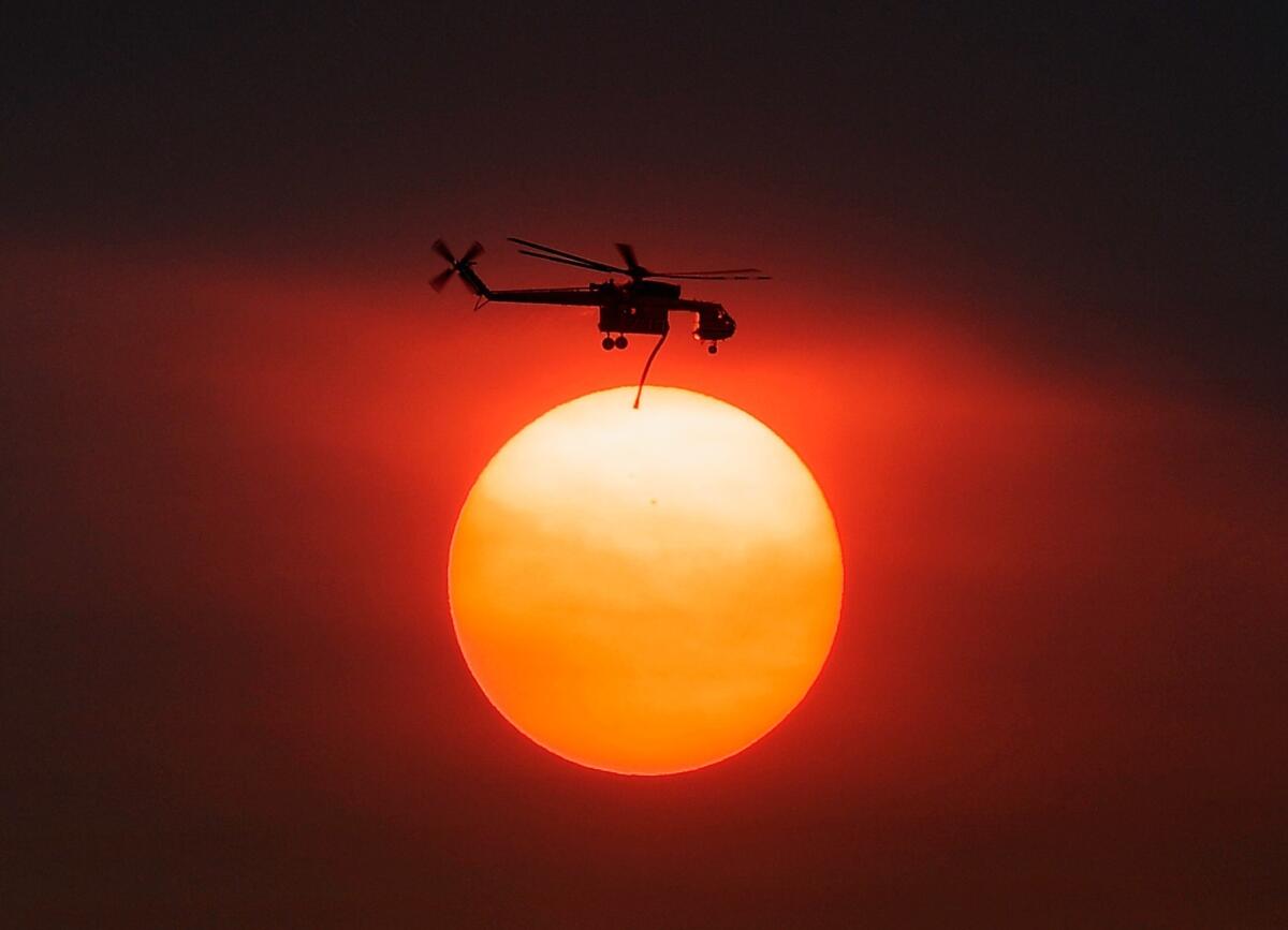 Smoke from the Mountain fire obscures the sun Thursday as a helicopter heads to battle the blaze.