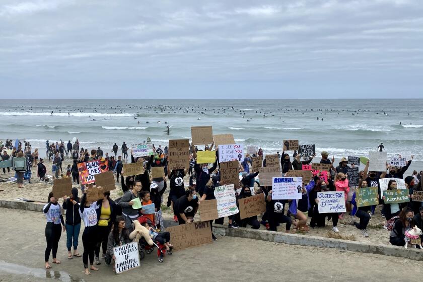 Protesters gathered with signs after the paddle out as surfers came back to shore.