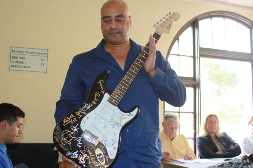 David Payne, organizer of the proposed jazz fest in Scripps Park, shows La Jolla Parks & Beaches board a signed guitar similar to one that would be auctioned off at the festival.