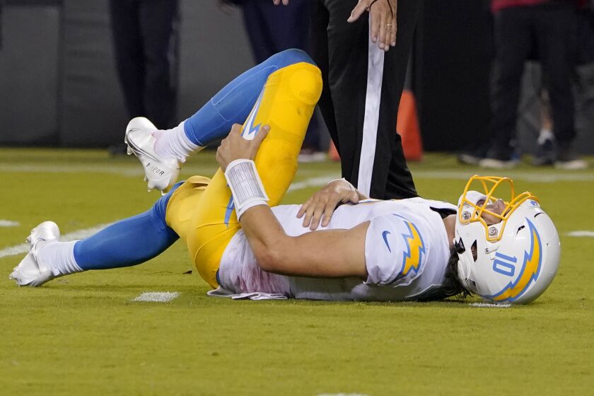 Los Angeles Chargers quarterback Justin Herbert holds his leg after being hit.