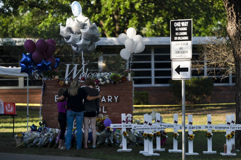 Una familia rinde homenaje frente a las cruces que llevan los nombres de las víctimas en la escuela 