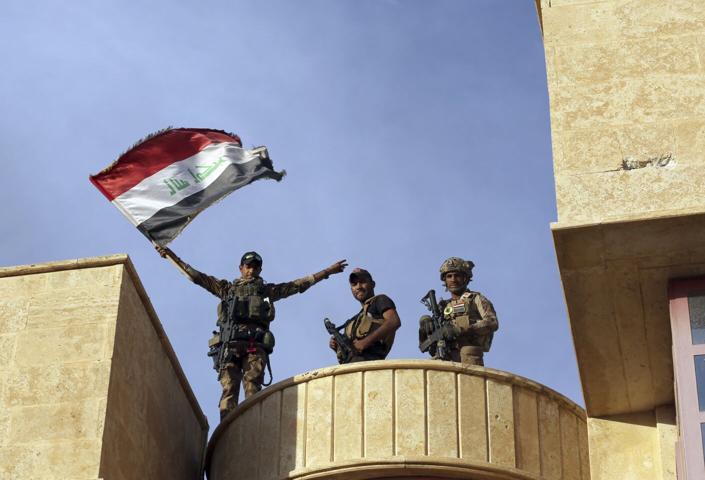 Iraq's elite counterterrorism forces raise an Iraqi flag after retaking Bartella, outside Mosul, Iraq.