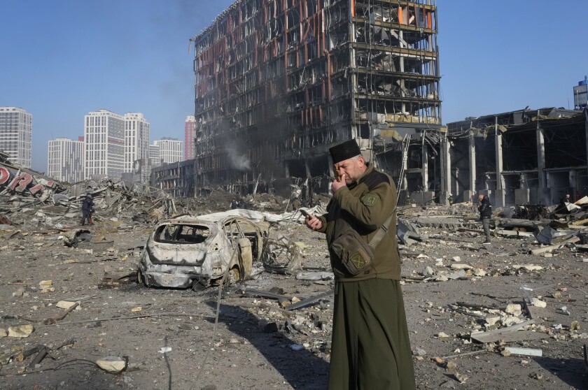 Un sacerdote reza junto a las ruinas de un centro comercial destruido tras un bombardeo, en Kiev,