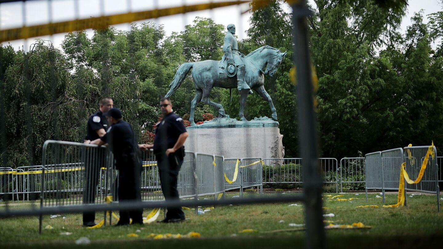 Police stand watch near the statue of Confederate Gen. Robert E. Lee in the center of Emancipation Park the day after the Unite the Right rally devolved into violence in Charlottesville. White nationalists had gathered in the city Saturday, in part, to protest the removal of the statue.