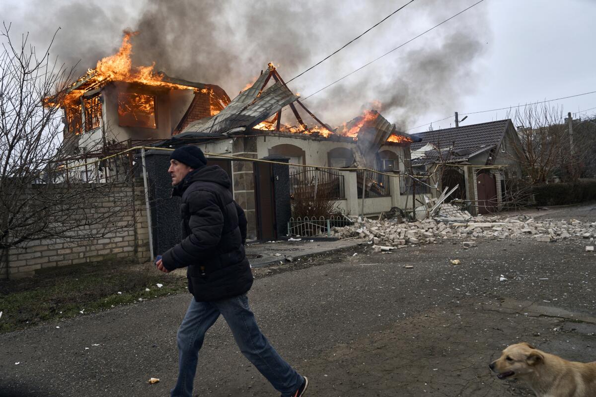 Un residente pasa junto a una casa en llamas tras un bombardeo ruso en Jersón, Ucrania,