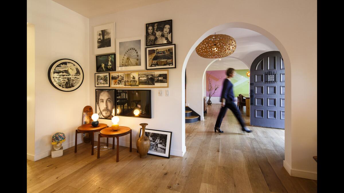 View from the living room through the entrance hallway to the dining room of Francois Moret and Anne Le Jeune's 1927 Spanish-style home in Los Feliz. In a corner of the living room, which has wide-planked oak flooring, are tables by Danish Modernist Jens Quistgaard, art by Raymond Pettibon and photographs by Nan Goldin, Larry Clark and Ed Templeton.