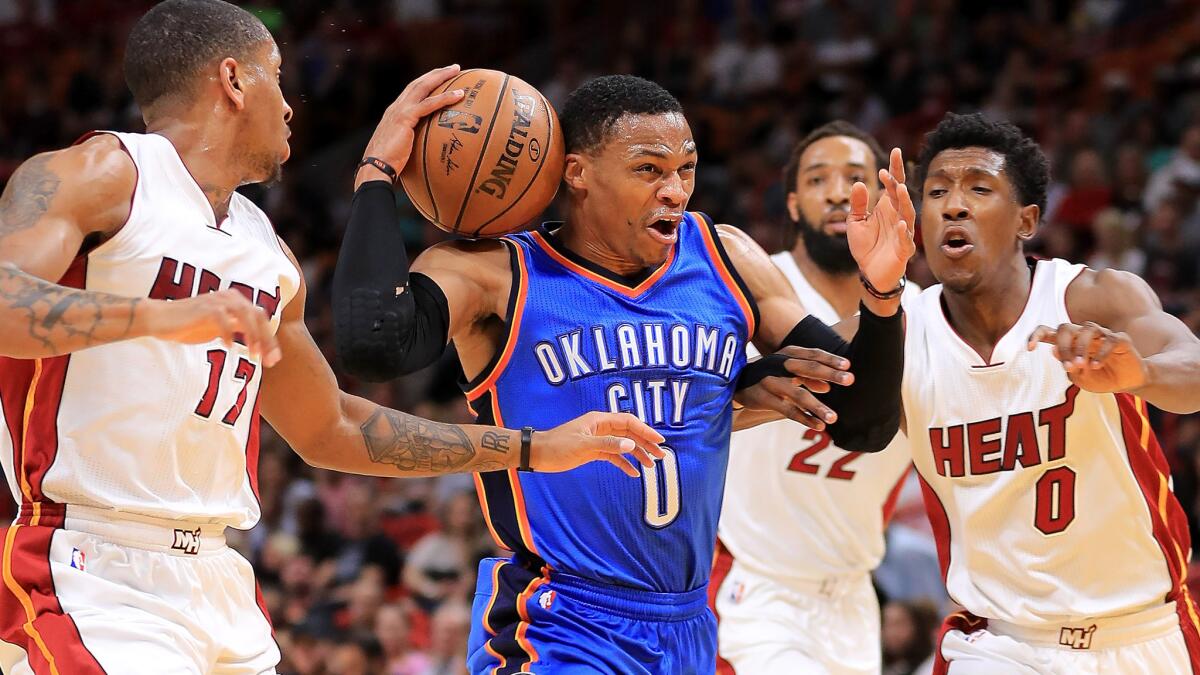 Thunder guard Russell Westbrook tries to keep control of the ball as he drives down the lane against the Heat's Rodney McGruder (17) and Josh Richardson (0) on Tuesday night.