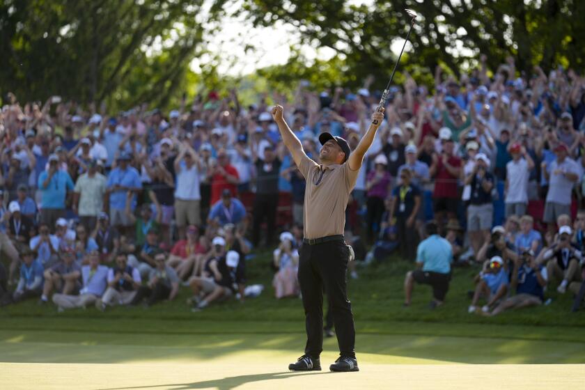 Xander Schauffele extends his arms in the air and celebrates after winning the PGA Championship golf tournament 