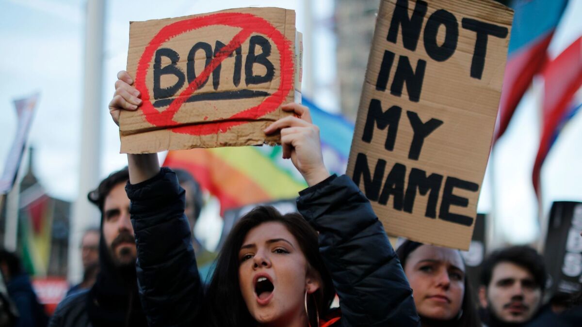 A protester demonstrating against Britain's military involvement in Syria holds a placard outside Parliament in London on April 16, 2018.