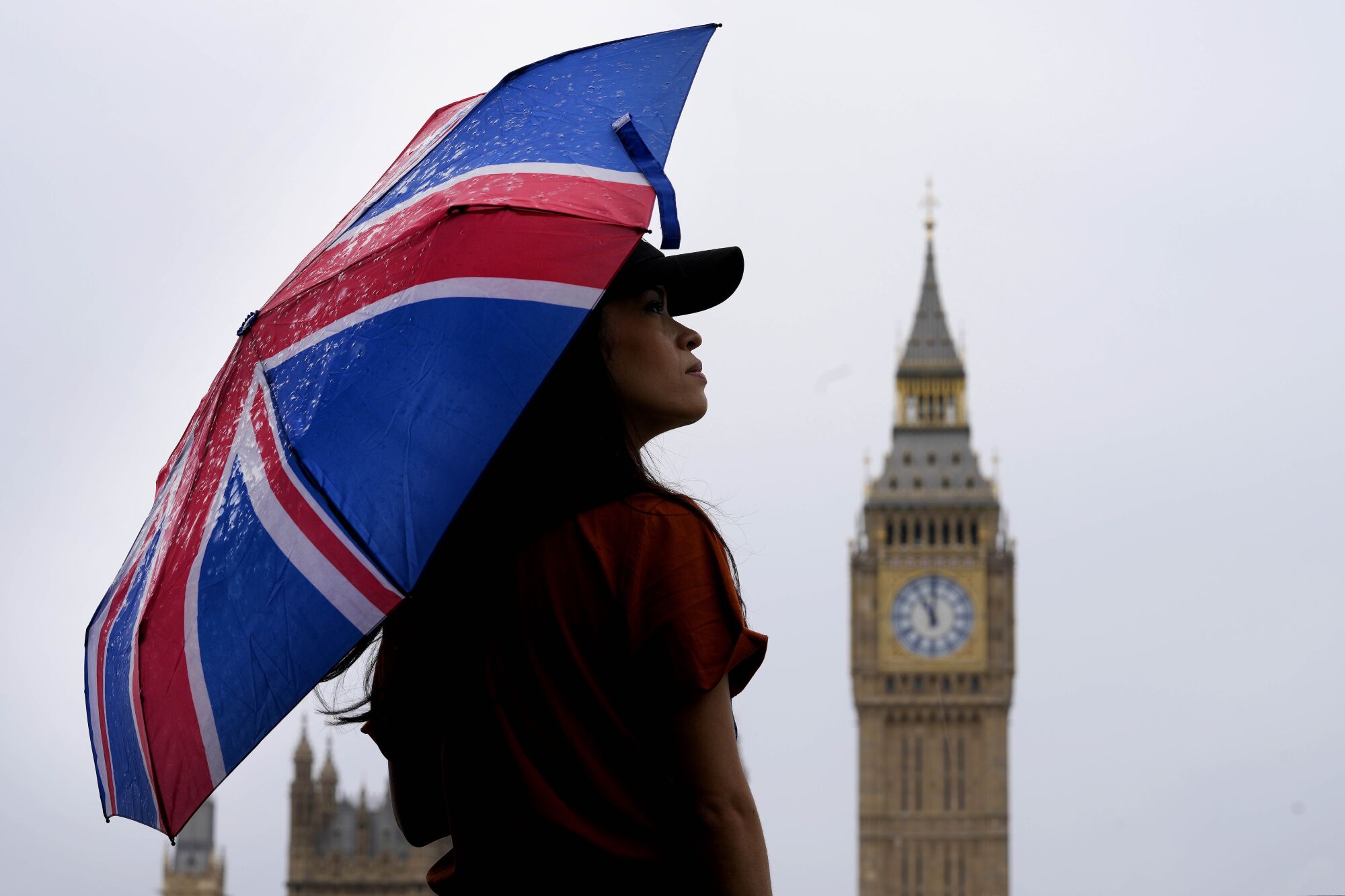 A woman uses an umbrella near Big Ben.