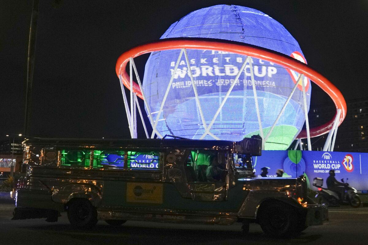 Una vehículo pasa frente a un despliegue de la Copa Mundial de basquetbol en Pasay, Filipinas, 