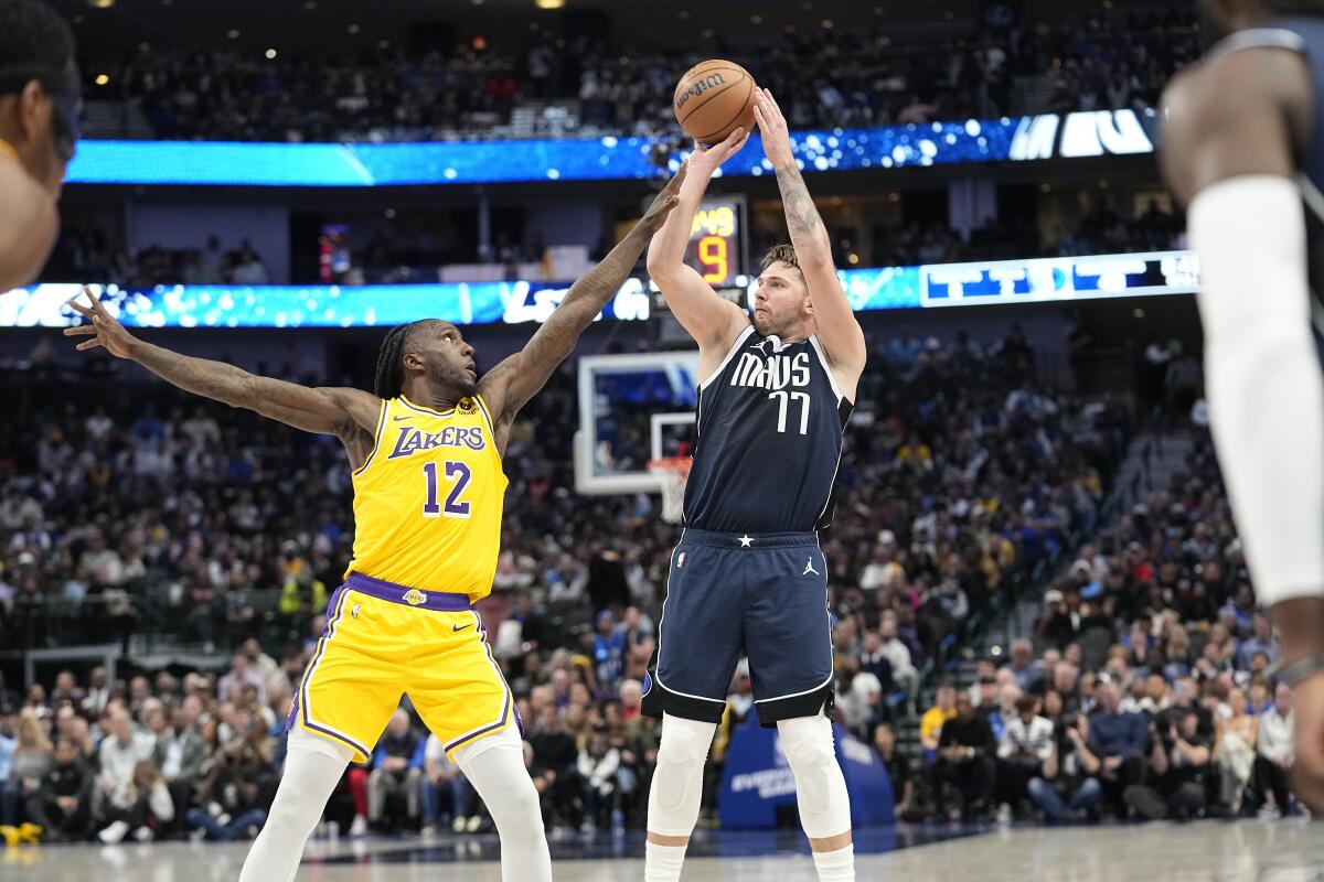 Mavericks guard Luka Doncic shoots while Lakers forward Taurean Prince puts a hand in his face