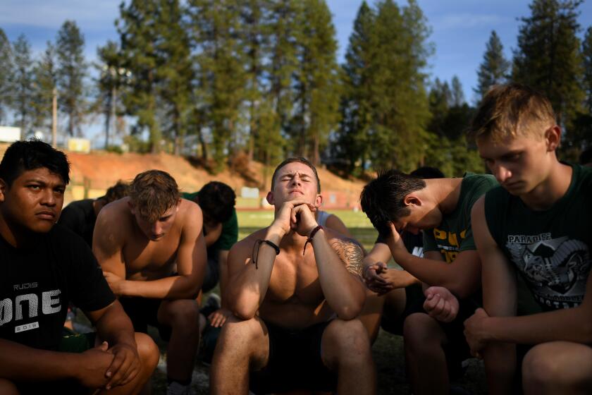 PARADISE, CALIFORNIA AUGUST 23, 2019-Lukas Hartley, center, listens to a coach give a pep talk before their first game of the season since the Camp Fire devastated the town last year. (Wally Skalij/Los Angeles Times)