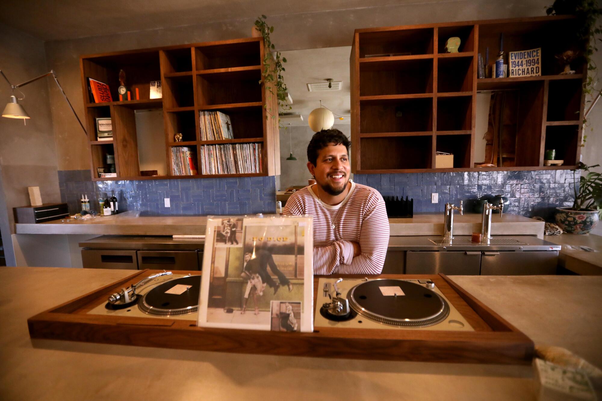 Adrian Romero, owner of Rosemary HiFi bar, sits at the bar that features two built-in turntables at the establishment.
