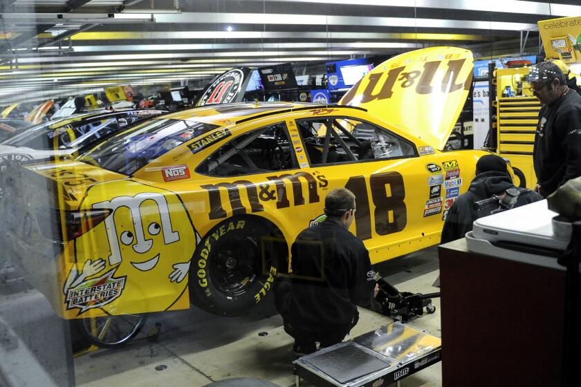 Crew members work on Kyle Busch's No. 18 car after it failed a post-qualifying inspection on Friday.