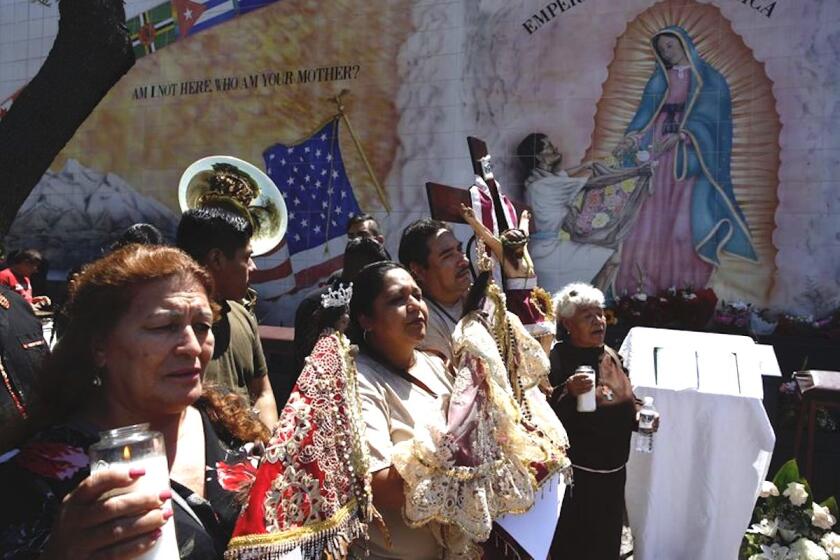 Migrantes hispanos rezan por las víctimas de balaceras en California, El Paso, Texas, y Ohio frente a la iglesia Nuestra Señora la Reina de los Ángeles en Los Ángeles.