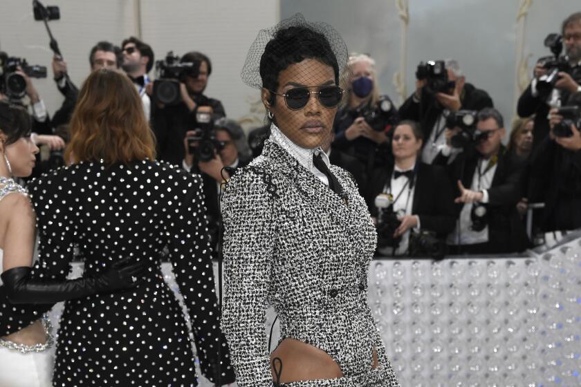 Teyana Taylor wears a sparkly silver gown, sunglasses and a fishnet veil on the Met Gala carpet