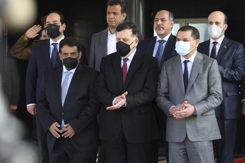 Libyan Prime Minister Abdul Hamid Dbeibah, front left, and former head of Libya’s UN-backed government Fayez Sarraj, center, and Mohamed al-Menfi, right, head of the new interim government’s presidential council, stand together after a ceremony marking the official handover of power to the new government, in Tripoli, Libya, Tuesday, March 16, 2021. Sarraj, the head of the Tripoli-based government, has been in conflict with a rival administration in the country’s East for years. Dbeibah’s interim government is to replace the country’s two rival administrations and lead the war-torn North African nation through elections later this year. (AP Photo/ Hazem Turkia)