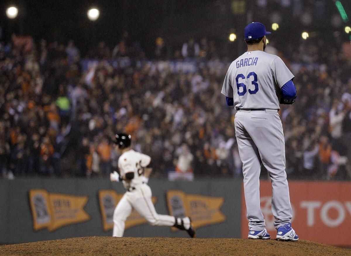 Dodgers reliever Yimi Garcia watches as Giants catcher Buster Posey rounds the bases after hitting a two-run homer in the seventh inning. The Giants won, 4-0.