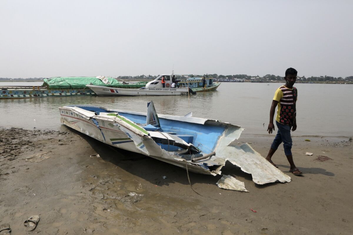 A man walks past the mangled remains of a speedboat that overturned Monday morning after hitting a cargo boat in River Padma at the Kanthalbari ferry terminal in Madaripur, central Bangladesh, Monday, May 3, 2021. More than two dozen people were killed. (AP Photo/Abdul Goni)
