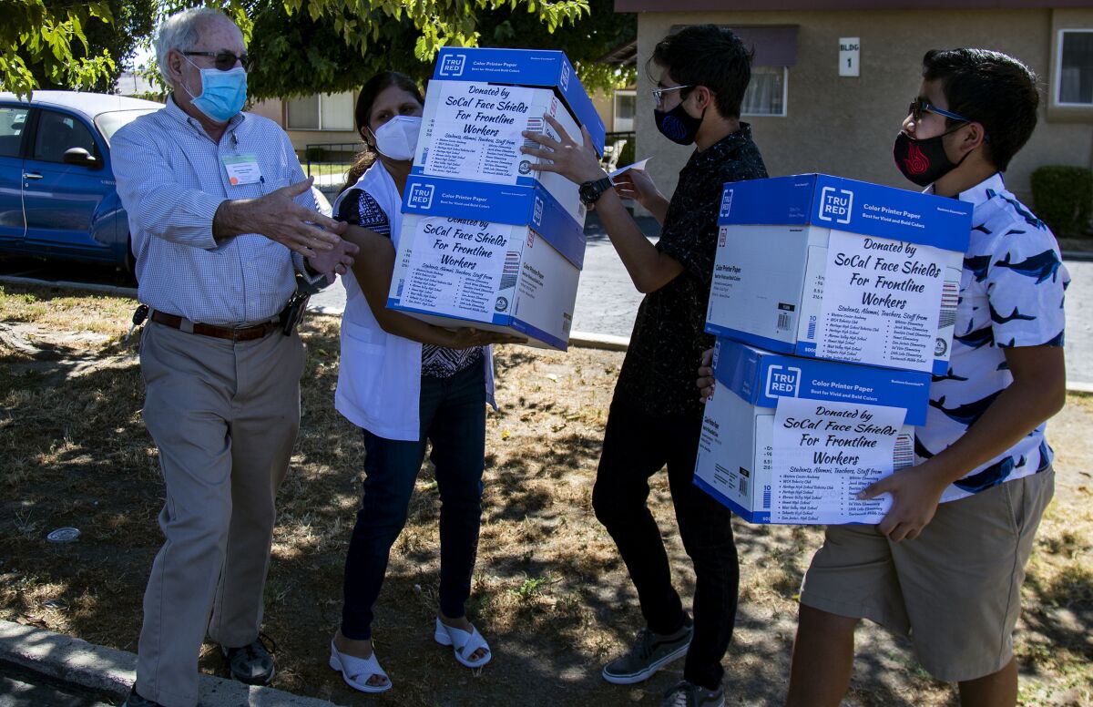 Zubin Carvalho, 14, left and his brother Tenzing, 12, donate boxes of their homemade face shields.