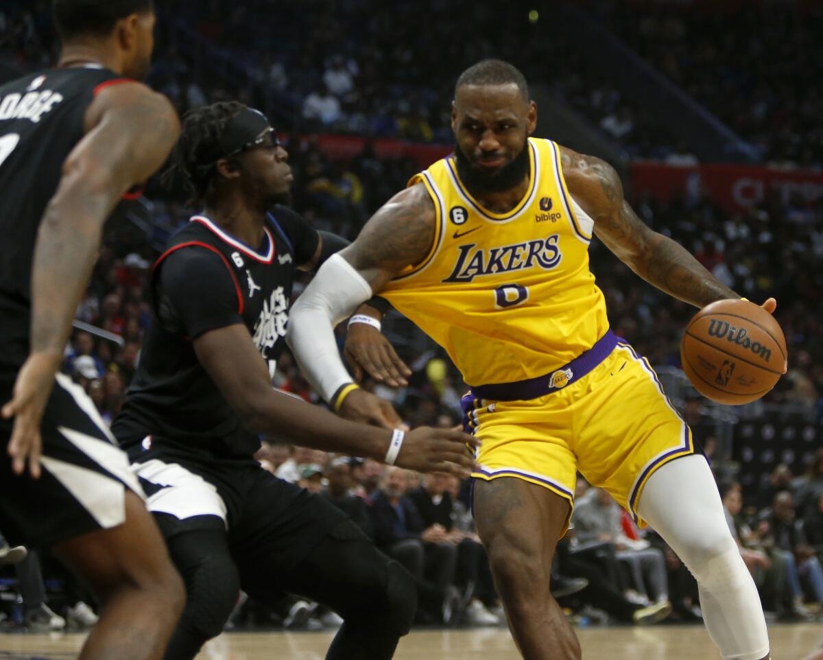 Lakers forward LeBron James tries to work the ball inside against Clippers defenders Paul George and Reggie Jackson.