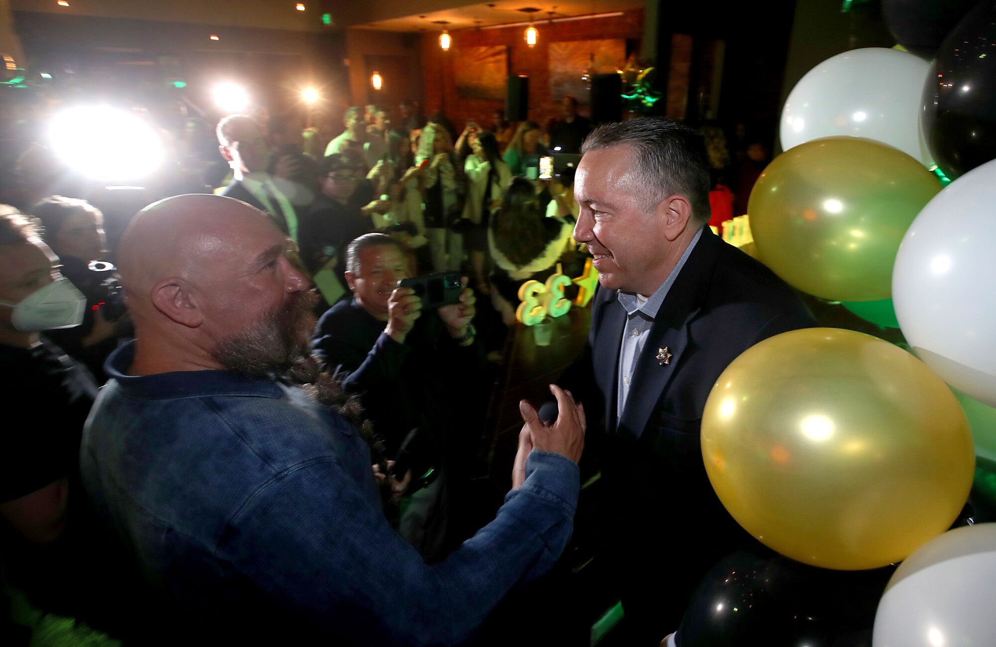 Two men greeting each other surrounded by a crowd and balloons
