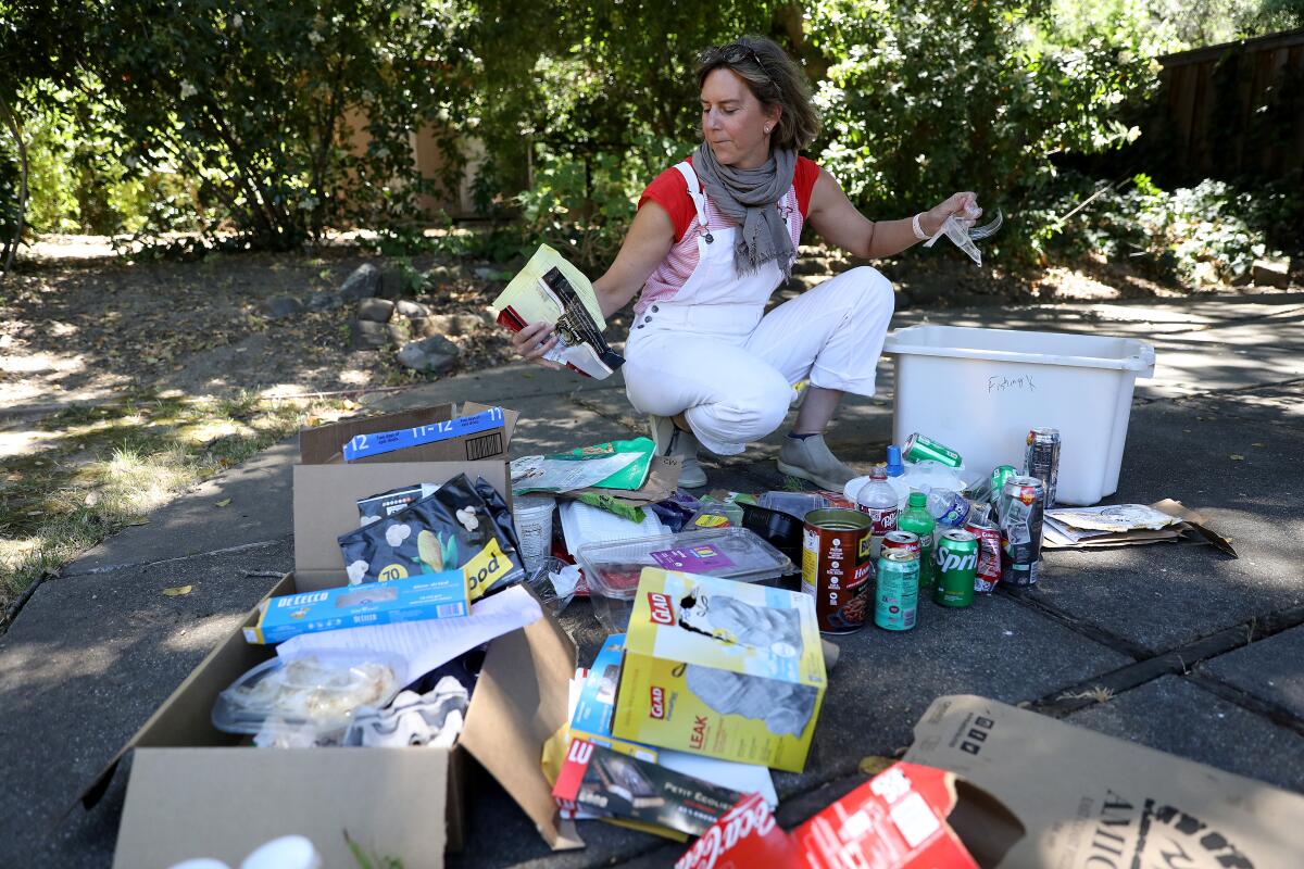 Susanne Rust crouching down to sort her family's trash on the ground 
