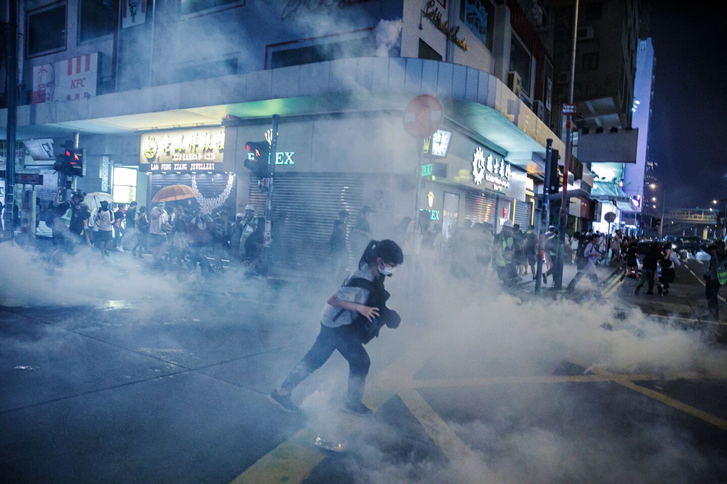 A woman runs through tear gas used by the Hong Kong police to disperse demonstrators, gathering in defiance of the upcoming China's national day, in the Wan Chai area of Hong Kong.